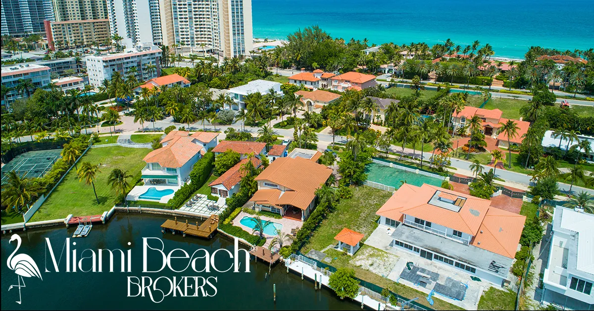 Aerial view of Miami Beach mansions with pools, palm trees, and waterfront canals. Logo: Miami Beach Brokers flamingo icon.