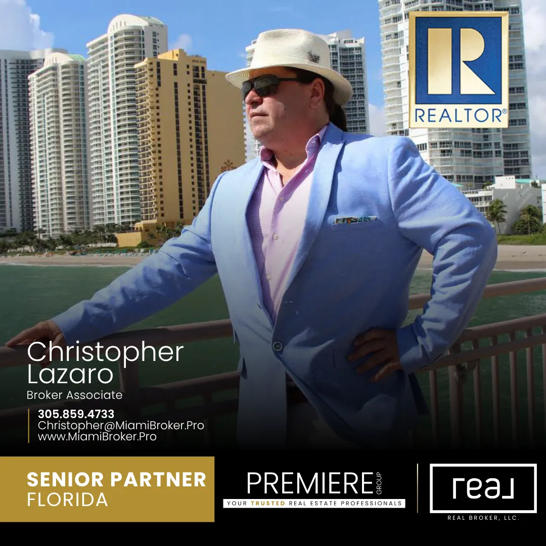 Man in blue suit and white hat stands on waterfront railing with high-rise buildings behind him. Realtor logo visible top right.
